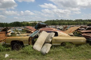 A sprawling junkyard with rows of old, abandoned cars illustrating the need for responsible recycling and disposal in car donations.
